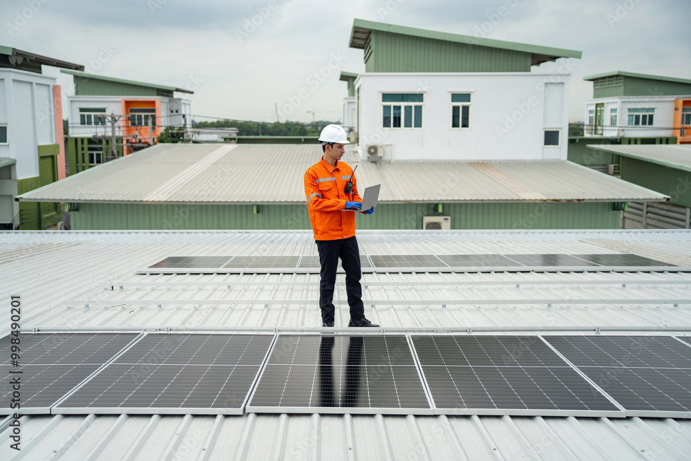Builder mounting photovoltaic solar modules on roof of house. Back view of man engineer in helmet installing solar panel system outdoors. Concept of alternative and renewable energy. Builder mounting photovoltaic solar modules on roof of house. Back view of man engineer in helmet installing solar panel system outdoors. Concept of alternative and renewable energy.