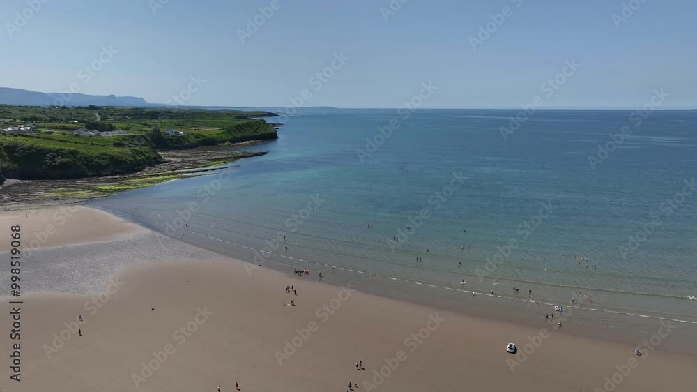 Rossnowlagh Beach, County Donegal, Ireland, June 2023. Drone orbits clockwise above the sandy beach as tourists swim and enjoy the water as light waves roll in under a blue sky with fluffy clouds. Rossnowlagh Beach, County Donegal, Ireland, June 2023. Drone orbits clockwise above the sandy beach as tourists swim and enjoy the water as light waves roll in under a blue sky with fluffy clouds.