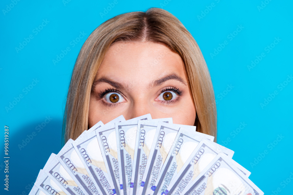 Photo portrait of attractive young woman cover face money fan dressed stylish striped clothes isolated on blue color background Photo portrait of attractive young woman cover face money fan dressed stylish striped clothes isolated on blue color background