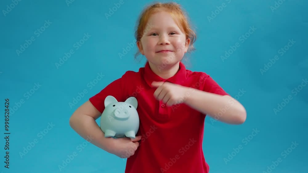A Cheerful Child Shares Savings Tips While Holding a Cute Blue Piggy Bank Against a Bright Backdrop A Cheerful Child Shares Savings Tips While Holding a Cute Blue Piggy Bank Against a Bright Backdrop