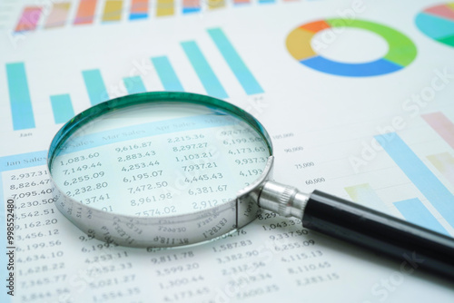 Magnifying glass on charts graphs paper. finance business.