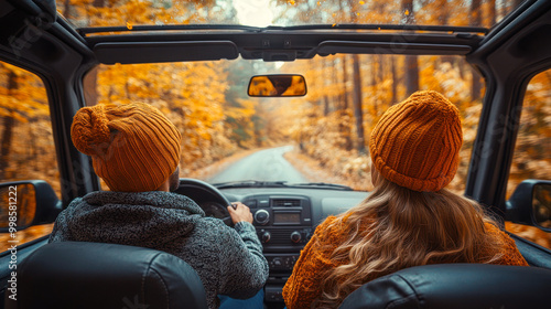Fototapeta Naklejka Na Ścianę i Meble -  Autumn car trip. Young couple driving and chatting in a vintage vehicle on the road through the autumn forest. Back view. car fall road, sun, concept car travel. going on vacation trip using car