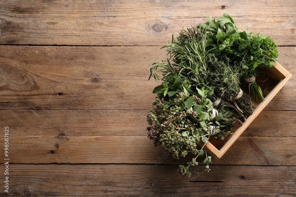 Bunches of different aromatic herbs in crate on wooden table, top view. Space for text Bunches of different aromatic herbs in crate on wooden table, top view. Space for text