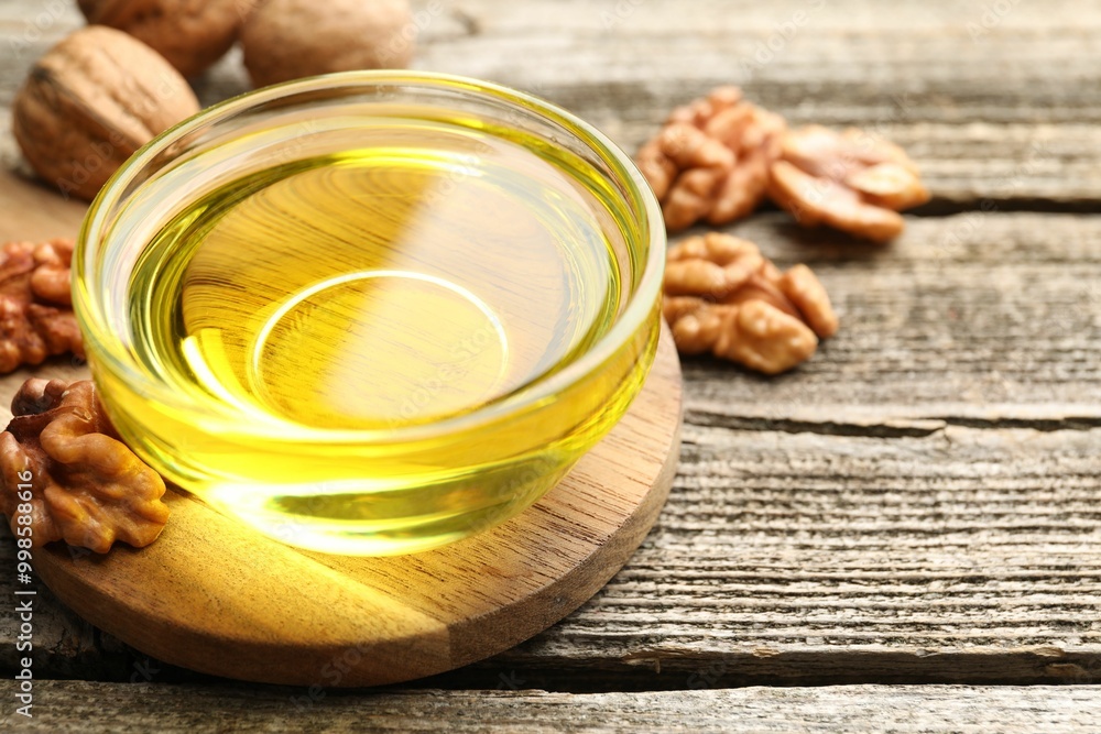 Cooking oil in bowl and walnuts on wooden table, closeup. Space for text Cooking oil in bowl and walnuts on wooden table, closeup. Space for text