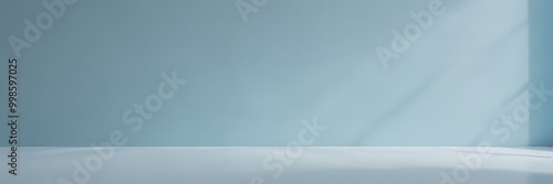 An empty room with a light blue wall and a white floor, featuring a window on the right side