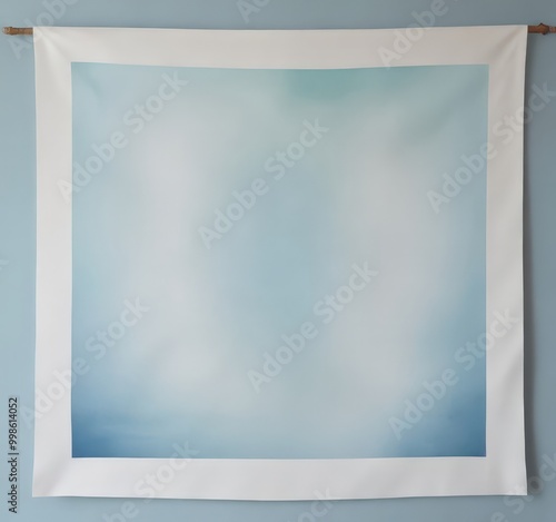 A large square canvas with a white border hangs on a light blue wall, featuring a gradient of blue and white colors