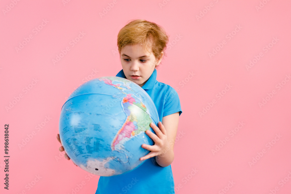 Boy looking at a globe against a pink background Boy looking at a globe against a pink background