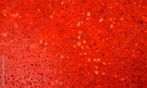 a close-up view red, speckled surface, possibly a stone or concrete floor, with a textured and irregular pattern photo