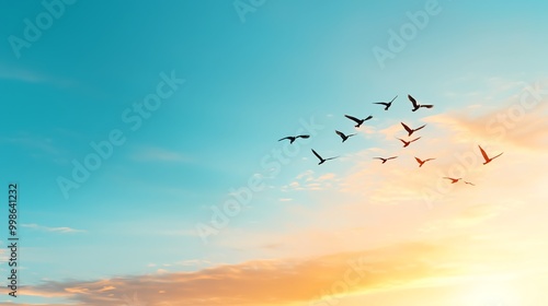 A flock of birds flying in formation against a vibrant blue sky and a warm sunset.