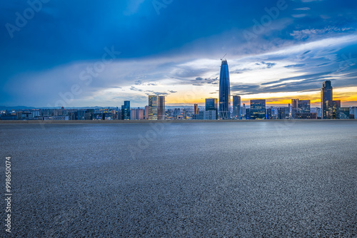 Empty asphalt road and cityscape with skyline in modern city at sunset