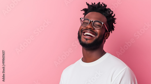 A man laughing nervously, his expression a mix of awkwardness and amusement, framed by a pastel pink background.
