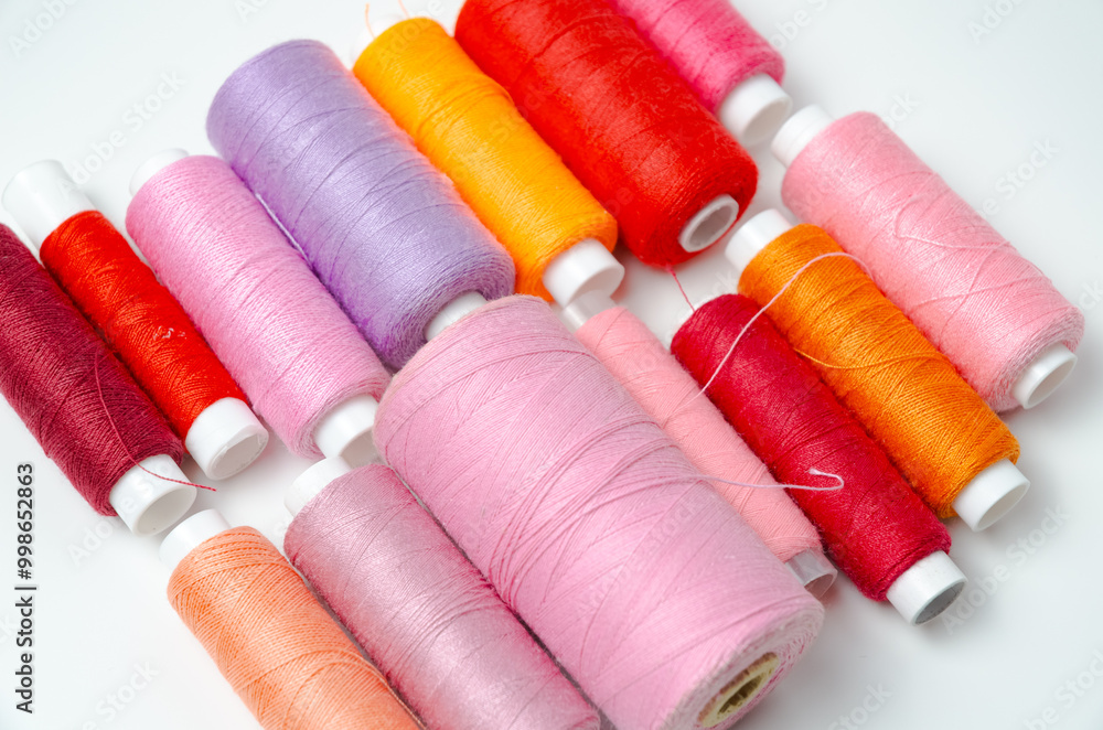 Pink and red thread spools on white background. Pink and red thread spools on white background.
