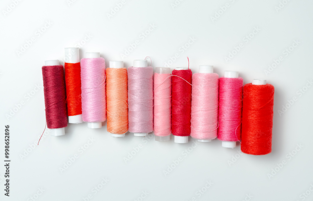 Pink and red thread spools on white background. Pink and red thread spools on white background.