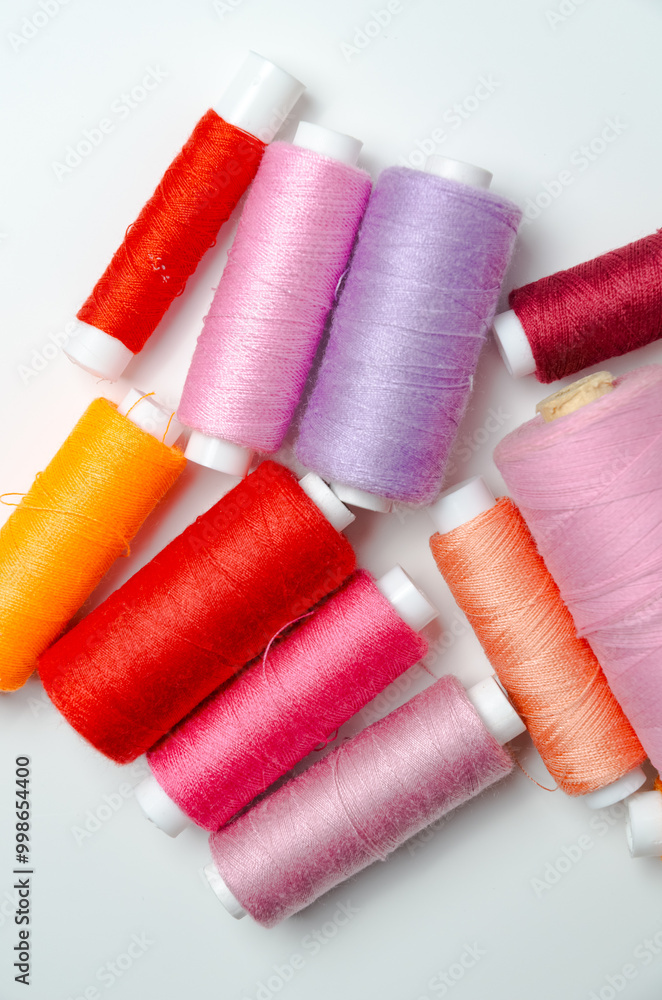 Pink and red thread spools on white background. Pink and red thread spools on white background.