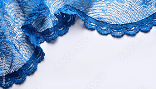 Beautiful white tablecloth with lace corners embroidered with cutwork on blue. Empty space for text. Blank frame. Close-up, top view, copy space, flat lay, mockup, panoramic view, banner photo