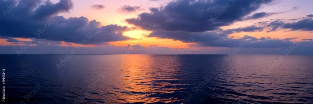 Obraz premium A serene sunset over the ocean, with the sun's rays reflecting on the calm waters