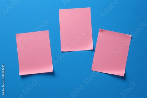 three pink sticky notes are on a blue surface