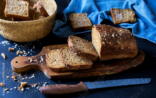 geschnittenes vollkornbrot auf einem holzbrett mit brotmesser und korb photo