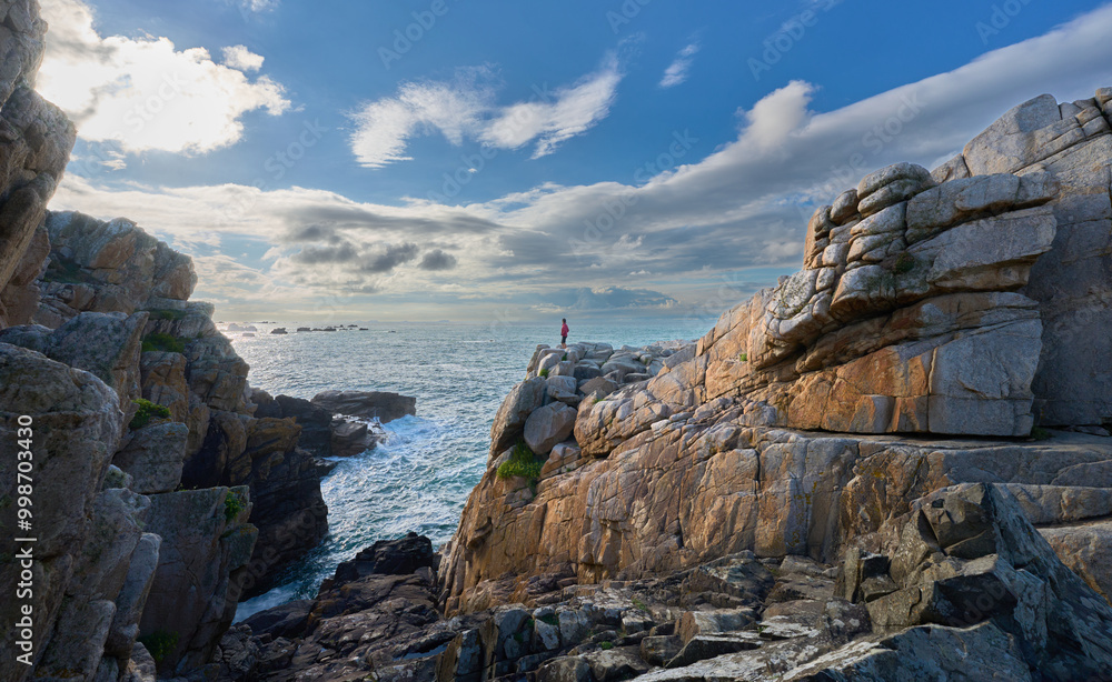 hiking woman resting during a hike and admiring the rocky landscape of rose granite coast of Le Gouffre de Plougrescant, Brittany, France hiking woman resting during a hike and admiring the rocky landscape of rose granite coast of Le Gouffre de Plougrescant, Brittany, France