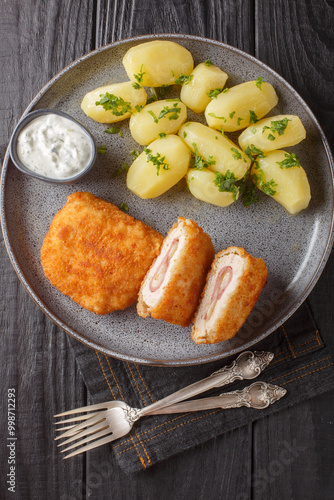 Obraz na płótnie Classic cordon bleu with new potatoes and cream sauce close-up on a plate on a table. Vertical top view from above w salonie