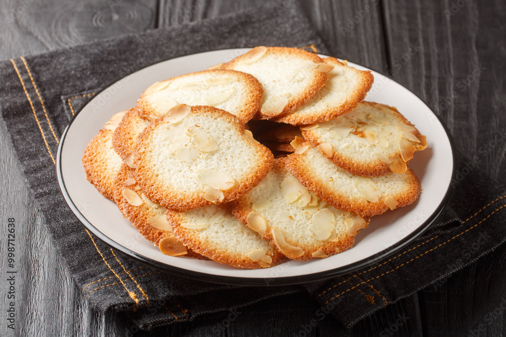 Fresh homemade French almond tuile cookie closeup on the plate on the table. Horizontal