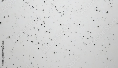 a close-up view white surface with numerous small black dots scattered across it, creating a speckled pattern