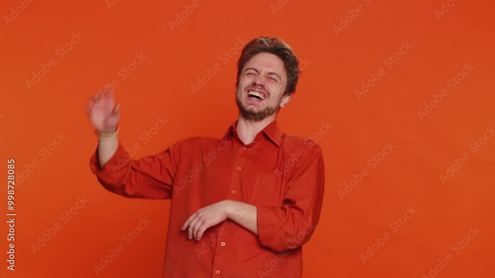 Happy Caucasian young man laughing out loud after hearing ridiculous anecdote, reaction on funny joke, feeling carefree amused. Positive people. Handsome guy isolated on studio orange background Happy Caucasian young man laughing out loud after hearing ridiculous anecdote, reaction on funny joke, feeling carefree amused. Positive people. Handsome guy isolated on studio orange background