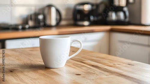 A closeup of a simple white coffee cup placed on a wooden kitchen table, highlighting a minimalist and calm lifestyle.