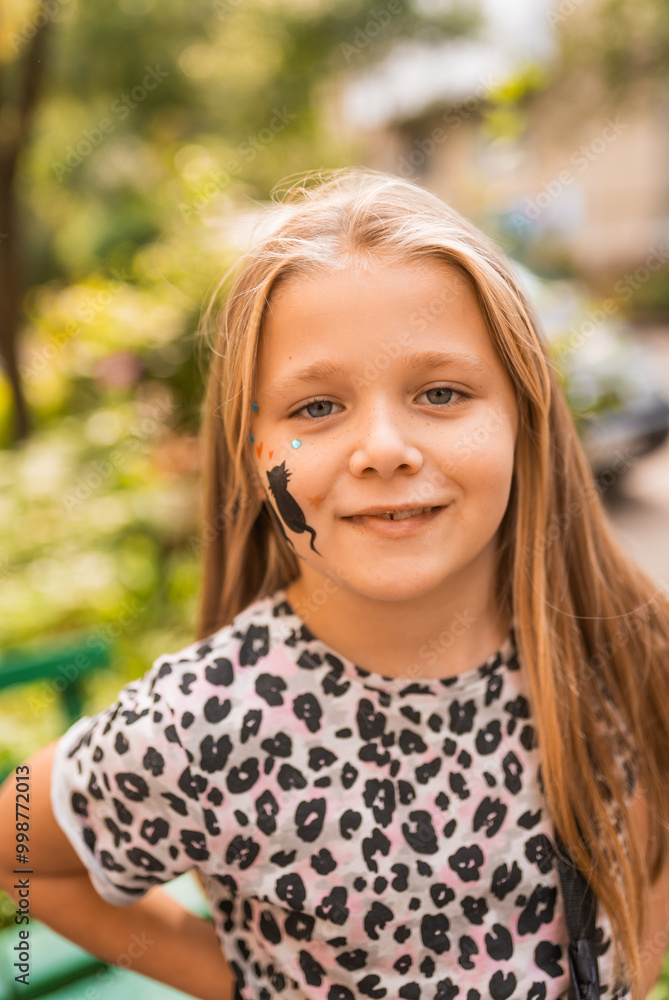 Portrait of a cute little girl with face painting of a cat outdoors. Child having fun at a party outside. Portrait of a cute little girl with face painting of a cat outdoors. Child having fun at a party outside.