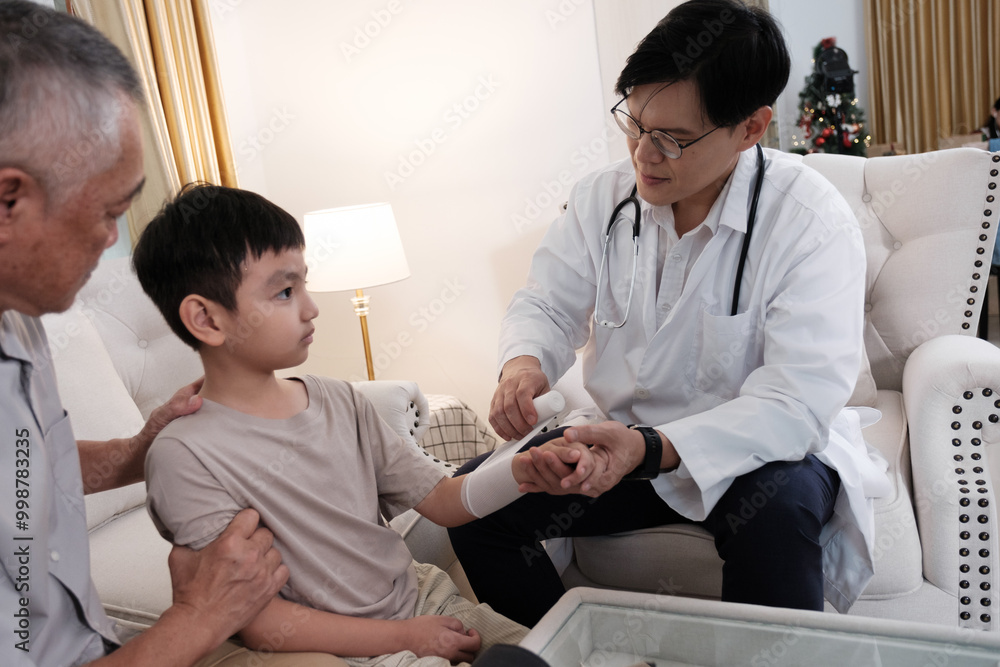 The doctor treats a wound on a boy's arm at home The doctor treats a wound on a boy's arm at home