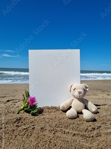 White canvas and crochet teddy bear on sandy beach