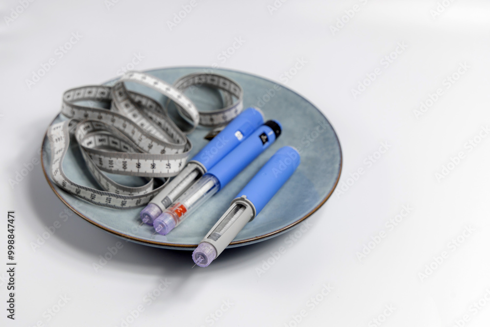 Naklejka premium Ozempic Insulin injection pen for diabetics and weight loss on a plate with a measuring tape
