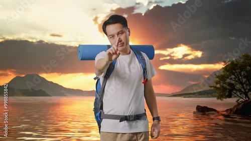 Asian Male Hiker With Mountaineering Backpack Showing No Gesture With Index Finger At A Lake photo