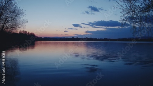 Tranquil lake at dusk with a pink sky and silhouette trees