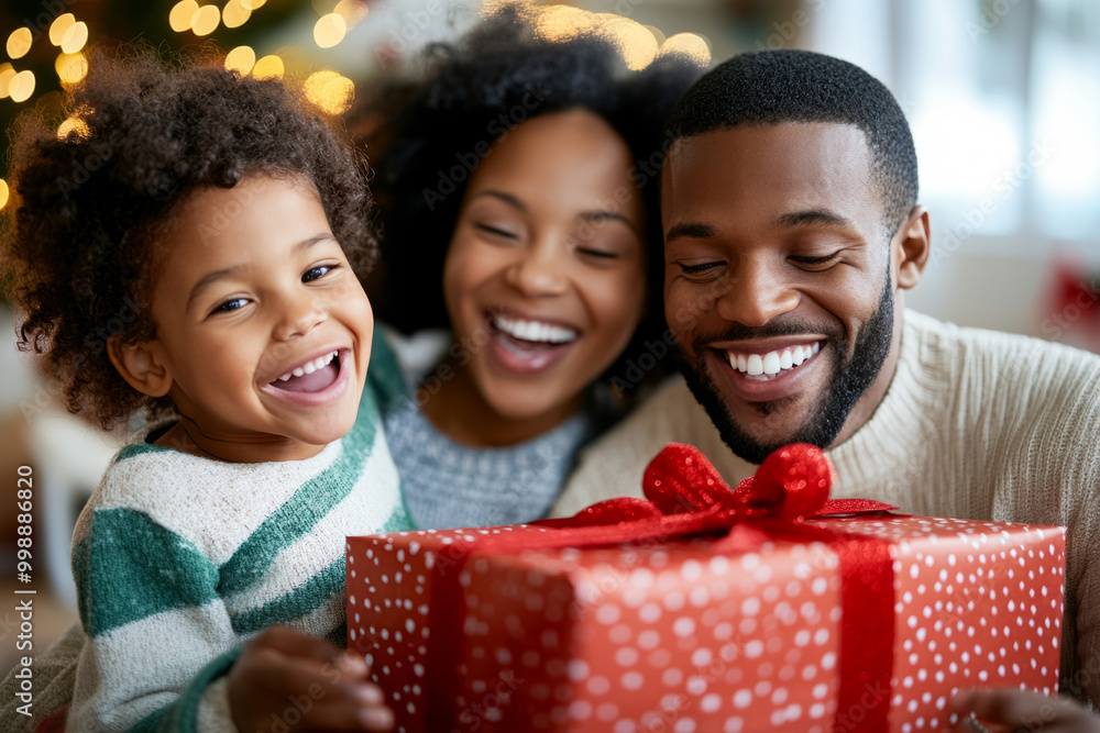 Joyful family with a child smiling as they open a festive red Christmas gift Joyful family with a child smiling as they open a festive red Christmas gift