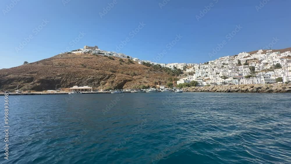 Greece, Astypalea, Castle and Town filmed outside of the harbor wall and from the sea on a sunny day with blue skies. Sea is deep navy blue and very calm. Greece, Astypalea, Castle and Town filmed outside of the harbor wall and from the sea on a sunny day with blue skies. Sea is deep navy blue and very calm.