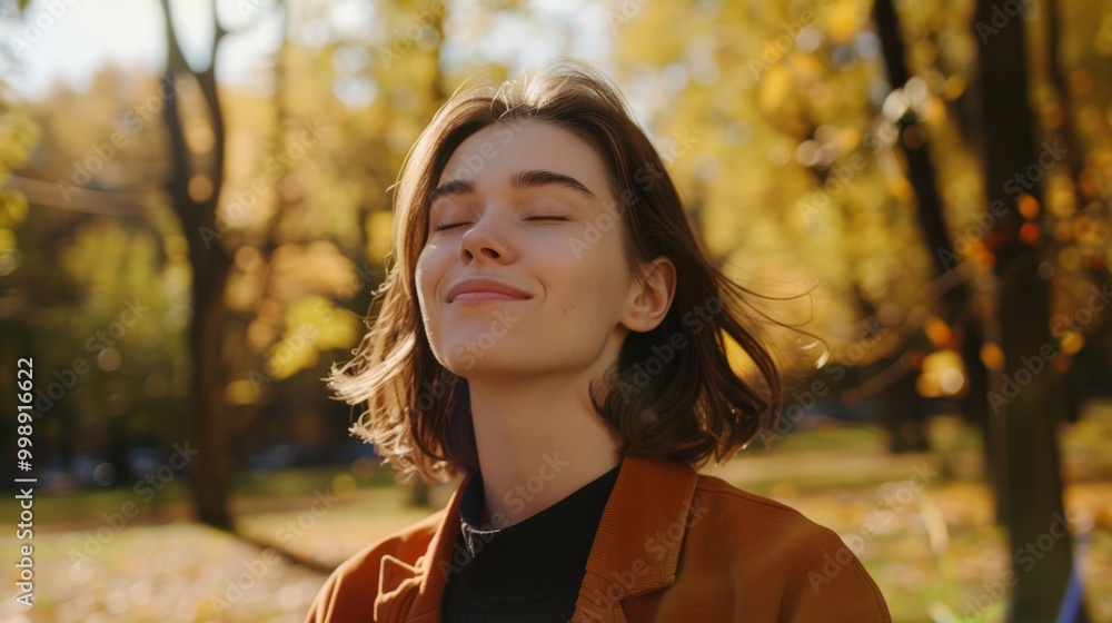 A young woman enjoys a serene moment in a sunlit park, eyes closed and a gentle smile, embraced by the warmth of autumn foliage. A young woman enjoys a serene moment in a sunlit park, eyes closed and a gentle smile, embraced by the warmth of autumn foliage.