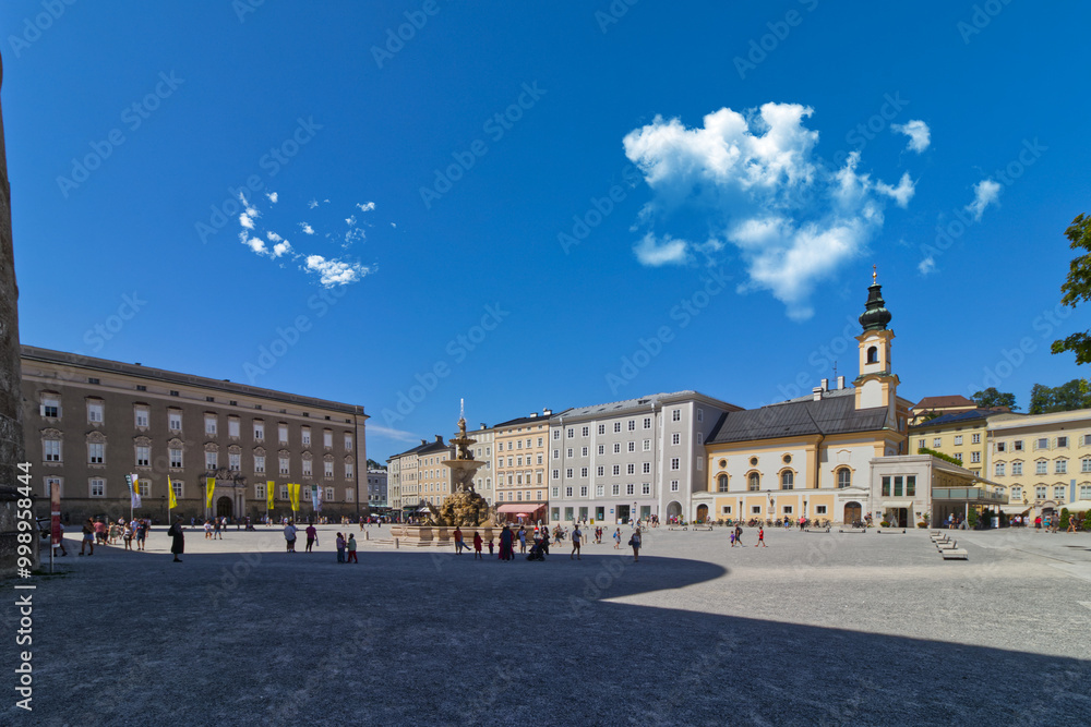Naklejka premium Clouds hover over the main square in Salzburg filled with tourists beating the sun, Salzburg, Austria