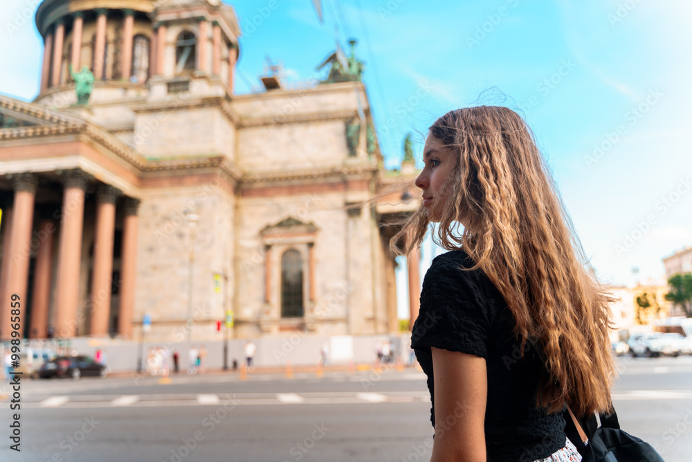 Young girl with long hair standing near St. Isaac's Cathedral in St. Petersburg. The concept of the tourist season, an active pastime. Young girl with long hair standing near St. Isaac's Cathedral in St. Petersburg. The concept of the tourist season, an active pastime.