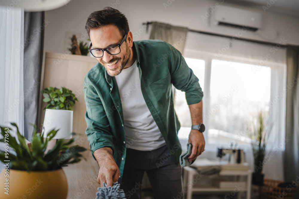 Adult man clean a desk with a microfiber cloth in a cozy living room Adult man clean a desk with a microfiber cloth in a cozy living room