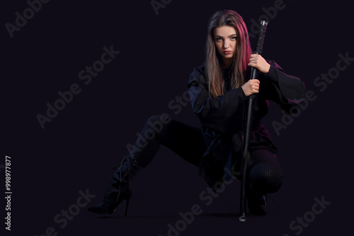 Beautiful sexy young woman with katana on dark background