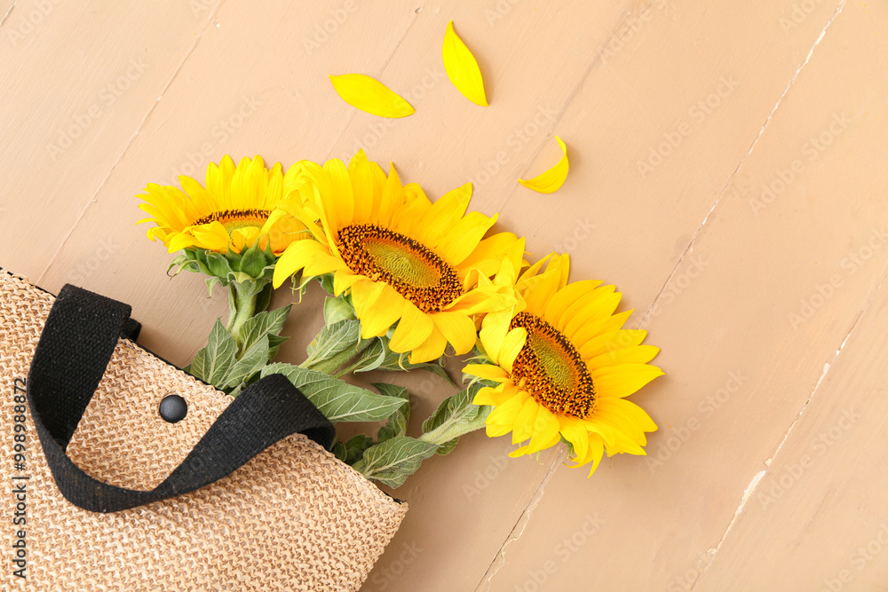 Εκτύπωση καμβά Stylish straw bag with beautiful sunflowers on beige wooden background