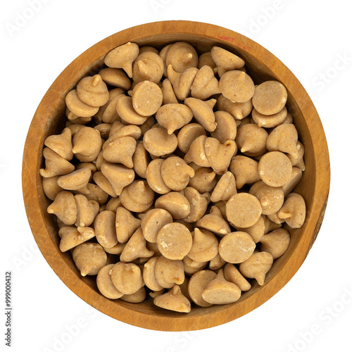 Overhead view of a small wood bowl filled with peanut butter baking chips isolated on a white background.