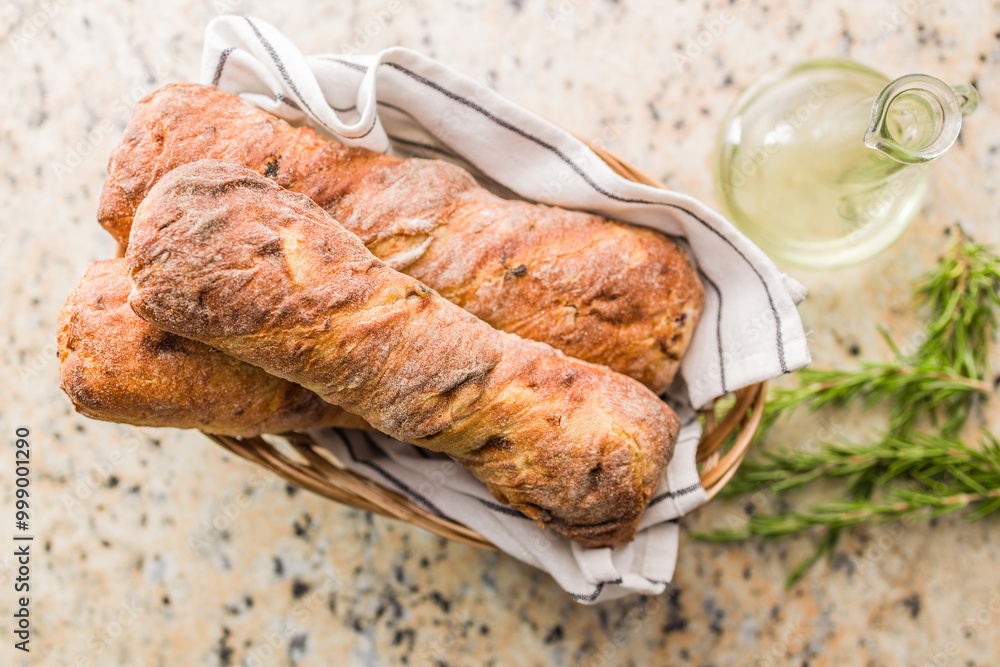 Crusty rustic baguette in basket on kitchen table. Top view. Crusty rustic baguette in basket on kitchen table. Top view.