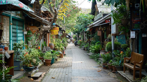 Narrow street with a lot of potted plants and benches. The street is lined with shops and has a lot of greenery