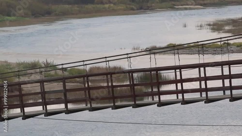 Suspension bridge over the taiga river. Extreme. 