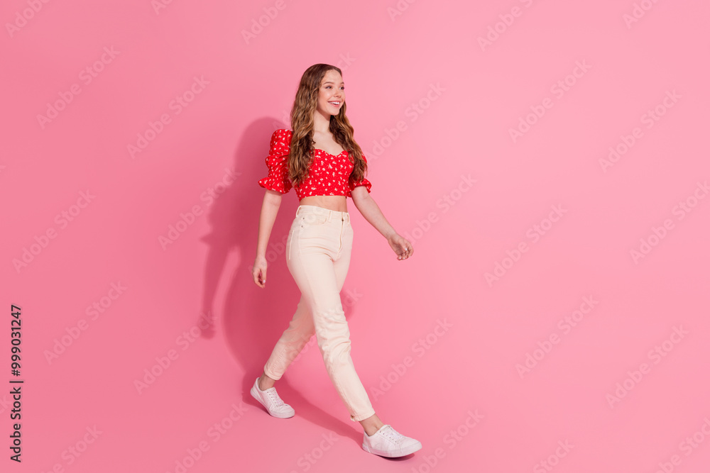 Full size photo of pretty teen girl walking model wear trendy red outfit isolated on pink color background Full size photo of pretty teen girl walking model wear trendy red outfit isolated on pink color background