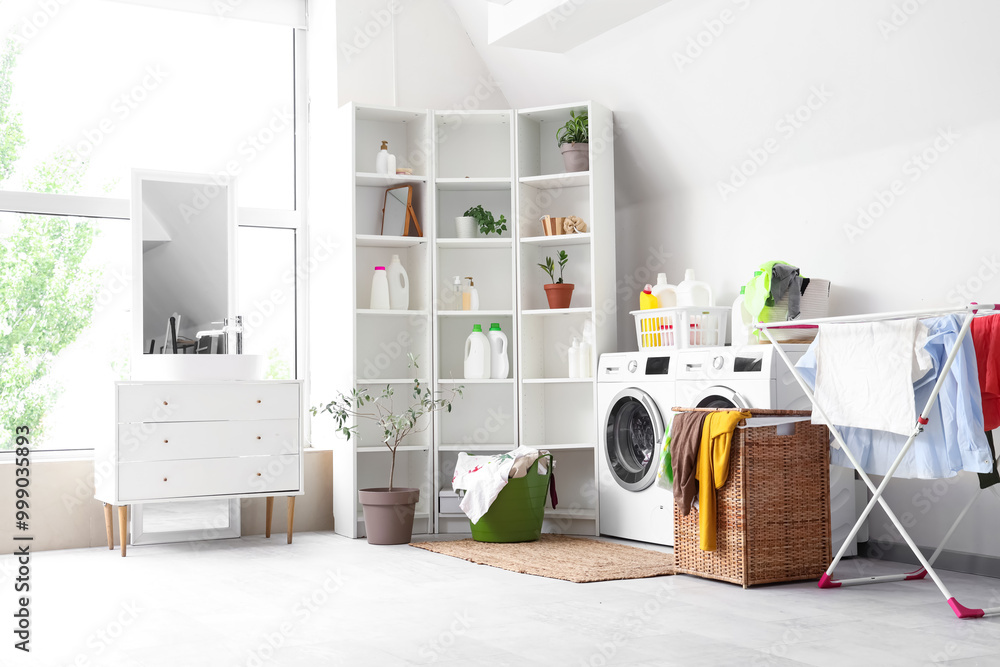 Obraz premium Interior of light bathroom with washing machines, laundry basket and dryer