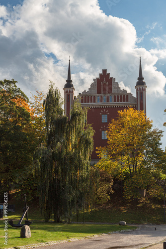 Admiralty House, golden trees and fallen leaves on Skeppsholmen islet in Stockholm by autumn cloudy day. Amiralitetshuset building near Skeppsholm bridge photo