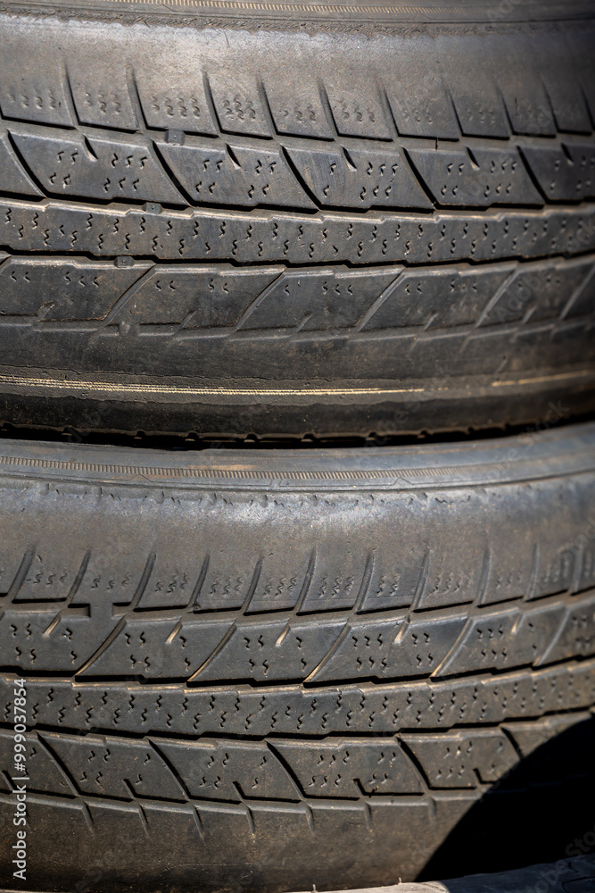 Worn and damaged tread of old tires lying in a landfill. Decreased road safety and environmental pollution from rubber waste